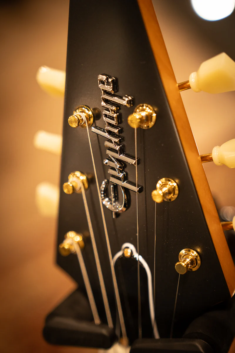 Close-up of the Epiphone 1958 Korina Flying V headstock with vintage-style tuners and Epiphone branding.
